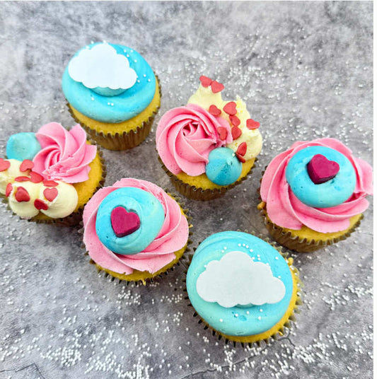 Each cupcake is baked fresh, swirled with dreamy pale pink and blue vanilla buttercream, topped with hearts and white sprinkles, and a handmade mini chocolate heart.